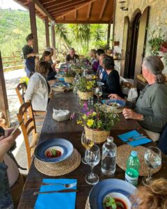 Gruppe von Menschen beim gemeinsamen Essen auf einer sonnigen Terrasse in Italien