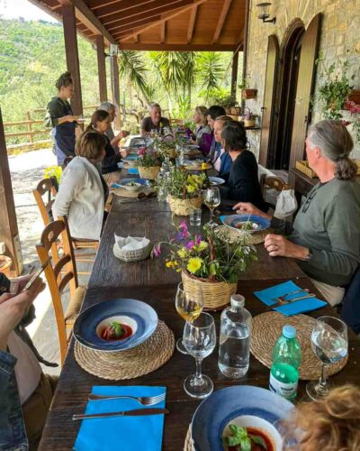Gruppe von Menschen beim gemeinsamen Essen auf einer sonnigen Terrasse in Italien